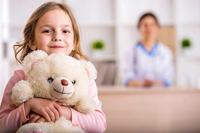 Little Girl Holding Teddy Bear Receiving Treatment from Group Insurance Plan